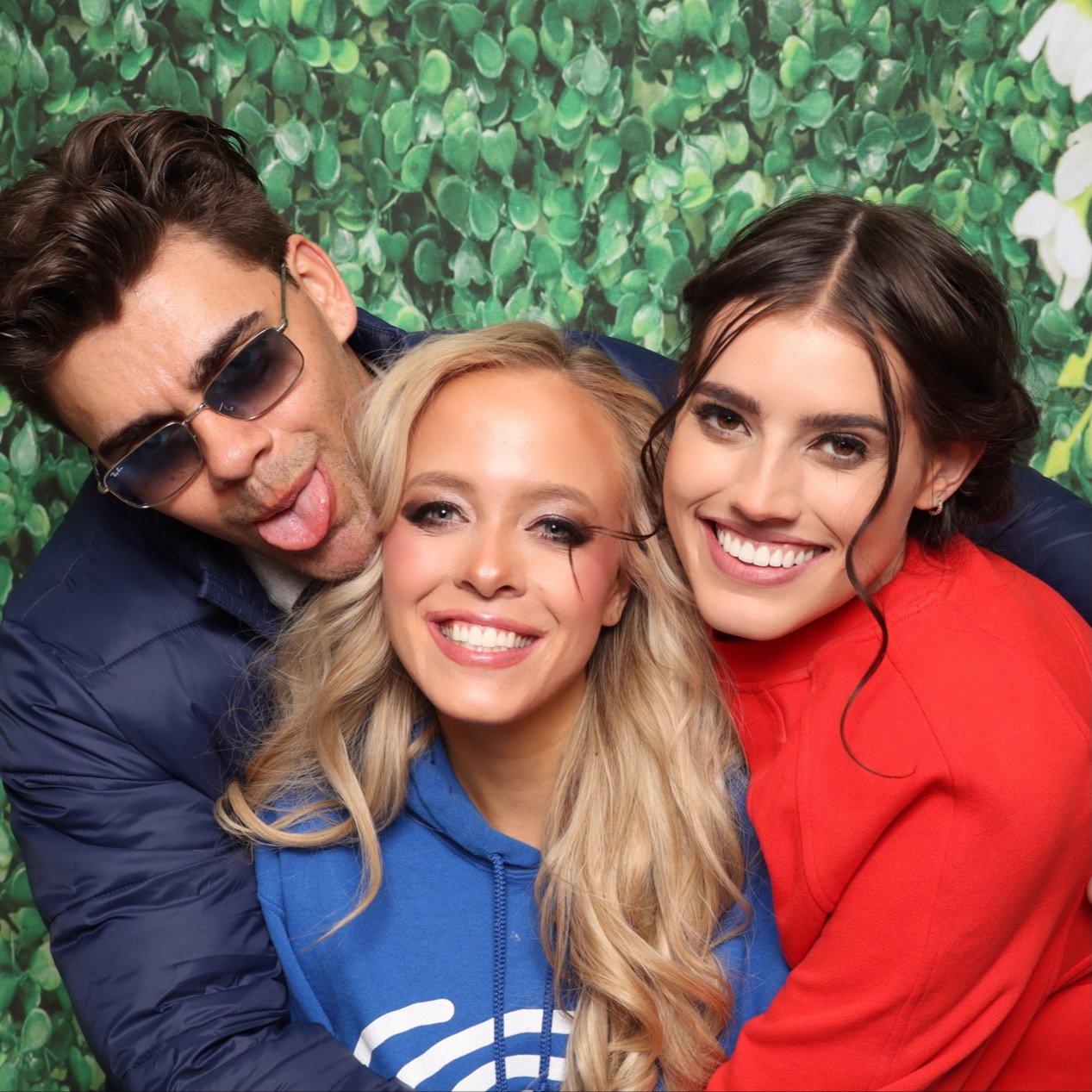 Three guests pulling faces at a greenery wall during an expo